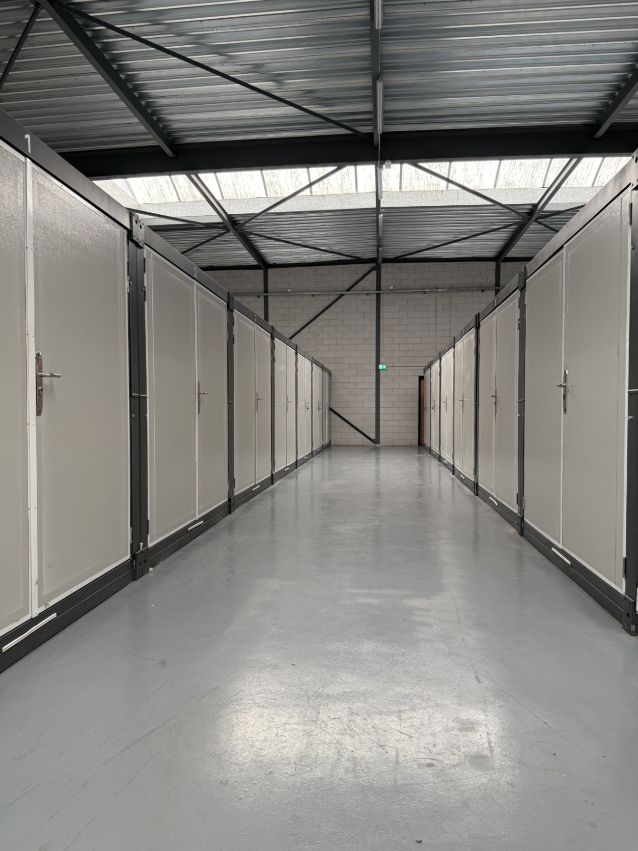 Lange, schone gang met goed verlichte opslagunits bij CB Storage